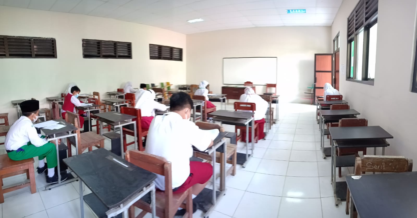 Calon peserta didik sedang mengerjakan soal tes yang diberikan pengawas ruangan.